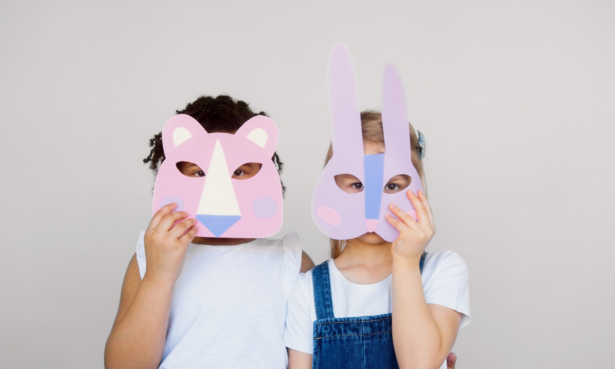 Zwei Kinder mit Maske vor dem Gesicht