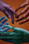 Eine rote, eine lila, eine blaue und eine grüne Hand greifen nach einander