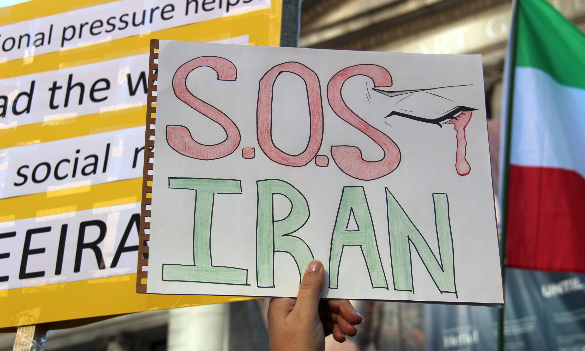 Beitragsbild: Schild Demomstration mit Aufschrift "S.O.S IRAN"